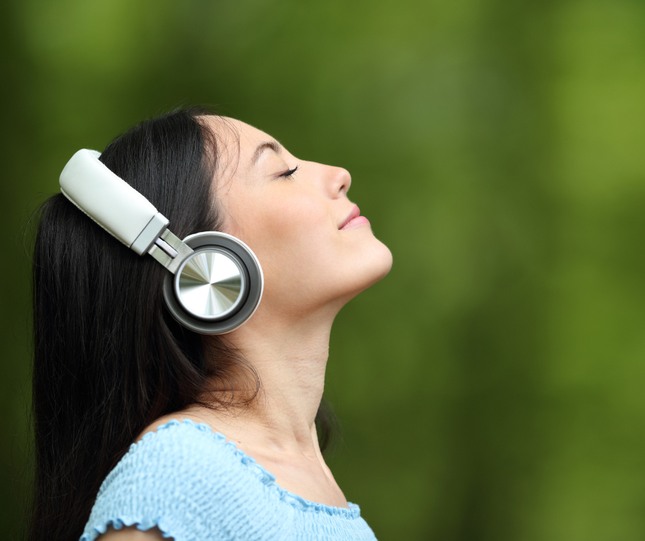 Woman with headphones, face lifted and eyes closed, completely at peace